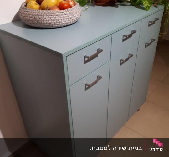 ארון אחסון נמוך צבוע בתכלת-ירקרק עם מגירות, דלתות וידיות מתכת